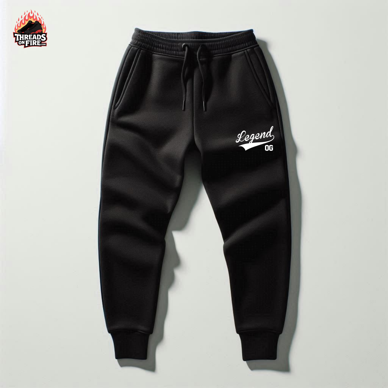 Black sweatpants with 'Legend OG' text on a light gray background, featuring Threads of Fire logo.